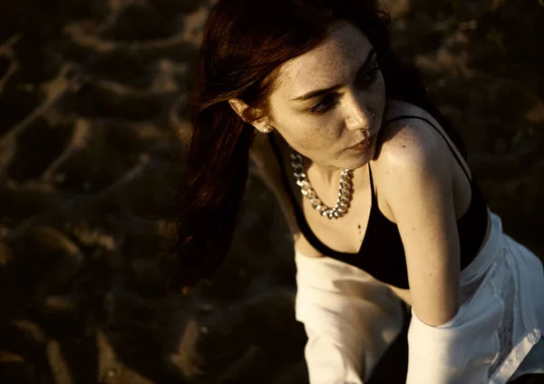 夕日のビーチを背景に砂の上で考えて白いシャツを着た赤毛の官能的な女の子 夏の季節 — ストック写真