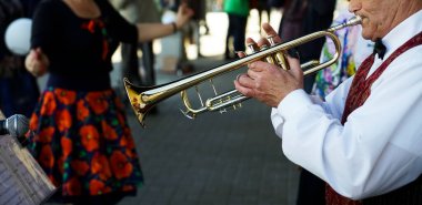 Yaşlı adam trompet çalıyor. Sokak arka planında Flugelhorn olan Caz Müzisyeni. 