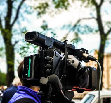 Video operatörü çalışıyor. Muhabir ve kamerası sokakta çalışıyor.