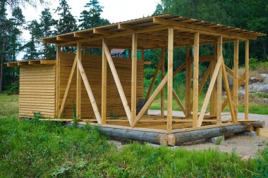 Yaz ormanlarındaki tahtalardan yapılmış bir ahır. - Rusya. Penceresiz ahşap hangar. Duvarlar doğal ahşaptan yapılmıştır.