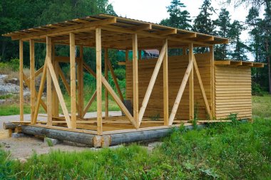 Yaz ormanlarındaki tahtalardan yapılmış bir ahır. - Rusya. Penceresiz ahşap hangar. Duvarlar doğal ahşaptan yapılmıştır.