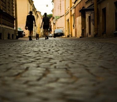 Köpeği tasmayla dolaştırmak. Şehir parke taşı. kaldırım taşları üzerinde yürüyen yayaların silueti. Saint Petersburg, Rusya.