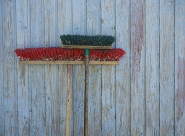 Mavi ahşap arka planda uzun tahta saplı iki tozlu süpürge. Ev işi için temizlik malzemeleri. plastik kıllı fırça