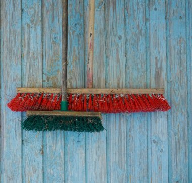 Mavi ahşap arka planda uzun tahta saplı iki tozlu süpürge. Ev işi için temizlik malzemeleri. plastik kıllı fırça