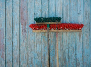 Mavi ahşap arka planda uzun tahta saplı iki tozlu süpürge. Ev işi için temizlik malzemeleri. plastik kıllı fırça