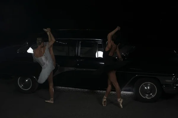 两名芭蕾舞演员深夜在复古车附近跳舞的画像 — 图库照片