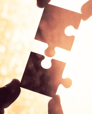 Gökyüzü arka planında yapboz parçaları olan eller.  