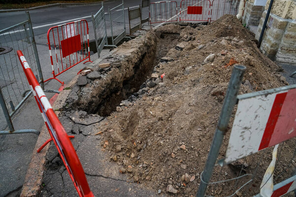 Дорога работает на городской улице. Раскопанная яма. 