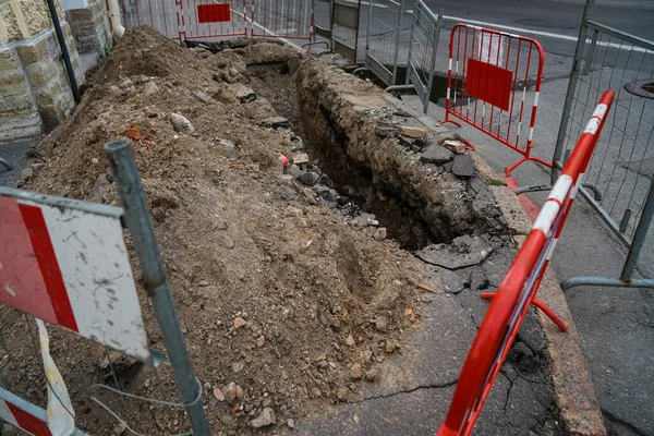 Road works on a city street. Fencing excavated pit.