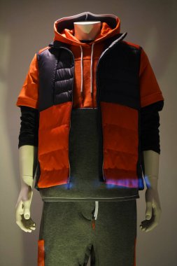 Erkek manken. Mavi ve turuncu kolsuz kapüşonlu kışlık ceket.