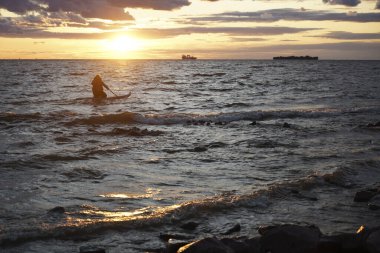 Gün batımı plajında renkli bir gün batımı. Okyanusta turuncu gün batımı. Renkli gün batımı. Kadın güvertede yüzüyor.