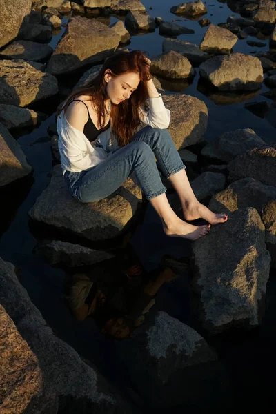 Uzun Kızıl Saçlı Kot Pantolonlu Güzel Bir Kadın Bir Kayanın — Stok fotoğraf