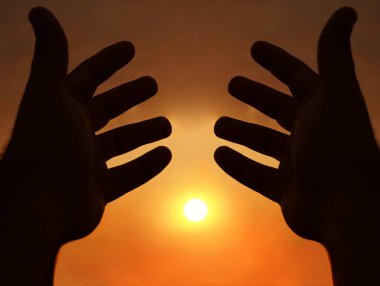 Güneşin arka planında iki el. İki erkek eli arasındaki güneş ışığı. güneşli gökyüzü arkaplanı