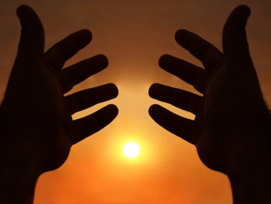 Güneşin arka planında iki el. İki erkek eli arasındaki güneş ışığı. güneşli gökyüzü arkaplanı