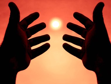 Güneşin arka planında iki el. İki erkek eli arasındaki güneş ışığı. güneşli gökyüzü arkaplanı