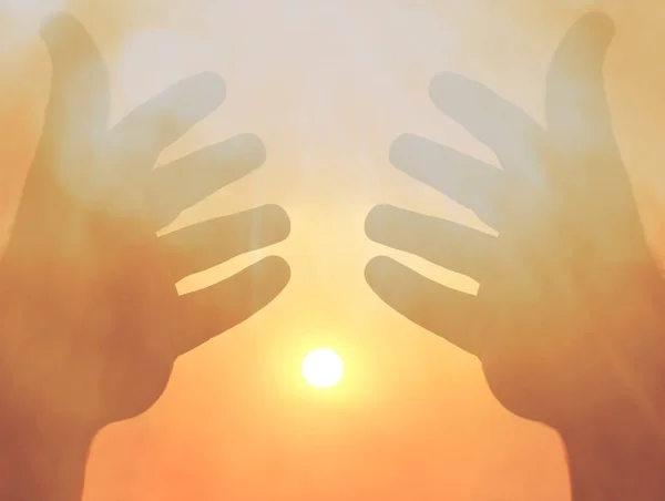 Two hands on a background of the sun. sunlight between two male hands. sunny sky background