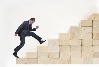 İşadamı kariyer basamaklarını tırmanıyor. Başarı yolunda takım elbiseli genç adam. İş büyümesini kavra.