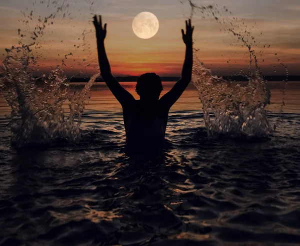 Black silhouette of woman. splashing water above head.  summer vacation. holiday active.  sea and sunset sky. Healthy happiness lifestyle. hands up.
