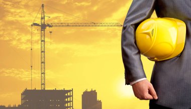 işçi güvenliği için sarı kask yeni bina ve inşaat vinç arka planda tutan mühendisi