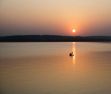 Aktif raket kullananlar. Siyah gün batımı silueti. Kız ve baba kürek çekerek ayağa kalkıyor.. 