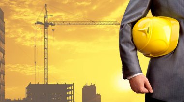 işçi güvenliği için sarı kask yeni bina ve inşaat vinç arka planda tutan mühendisi