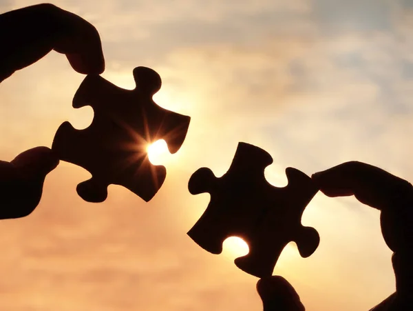 hands  with  puzzle pieces on sky background.