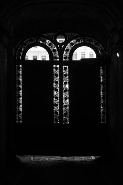Kapalı demir kapıları olan eski bir evde kemerli. Kavis demirinin ızgarasında kemer şeklinde batan güneşin ışınları çitleri delip geçer. Saint Petersburg.