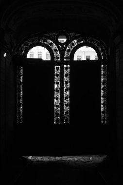 Kapalı demir kapıları olan eski bir evde kemerli. Kavis demirinin ızgarasında kemer şeklinde batan güneşin ışınları çitleri delip geçer. Saint Petersburg.