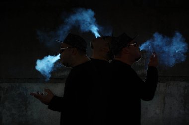 Siyah arka planda sigara içen adamın silüeti.