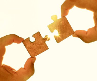 Gökyüzü arka planında yapboz parçaları olan eller.  