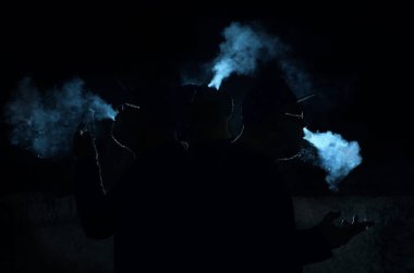 Siyah arka planda sigara içen adamın silüeti.