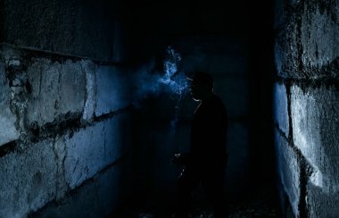 Siyah arka planda sigara içen adamın silüeti.