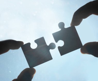 Gökyüzü arka planında yapboz parçaları olan eller.  