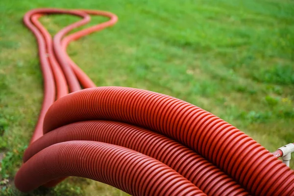 set of red corrugated pipes  on green grass meadow