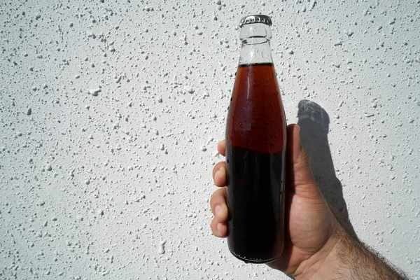 Чоловіча Рука Тримає Скляну Прозору Пляшку Кола Білому Тлі Стіни — стокове фото