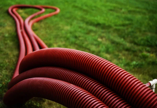 set of red corrugated pipes  on green grass meadow