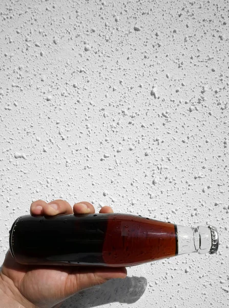 Botella Cola Transparente Vidrio Mano Masculina Sobre Fondo Pared Blanco — Foto de Stock