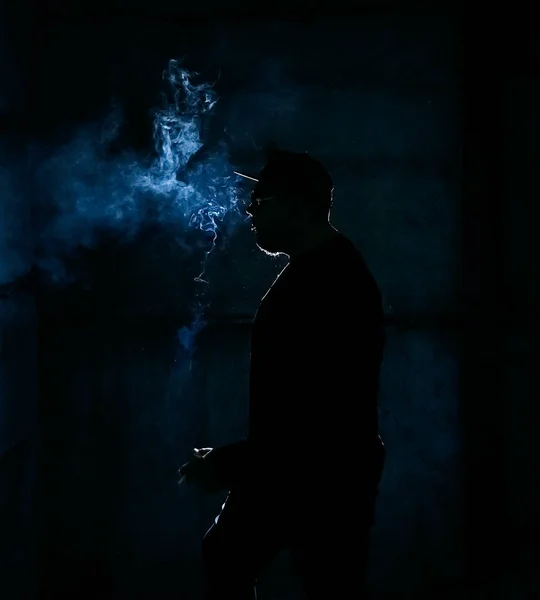 暗い背景でタバコを吸う男のシルエット — ストック写真