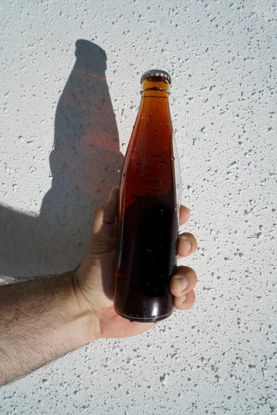 Botella Cola Transparente Vidrio Mano Masculina Sobre Fondo Pared Blanco — Foto de Stock