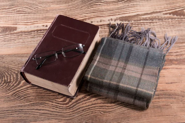 Bok, glasögon och halsduk på ett bord — Stockfoto