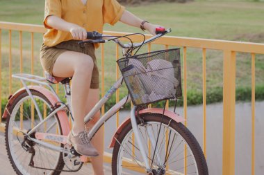Parkta bisiklete binen genç bir kadın. Arka planda yüz çiti yok.
