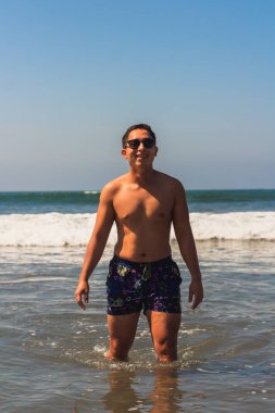 Yaz mevsiminde güneş gözlüğü takan gülümseyen genç Latin adam.