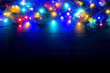Yılbaşı ışıkları arka planında bedava metin alanı var. Ahşap arka planda parıldayan renkli Noel ışıkları. Yeni yıl. Dekorasyon olayı için çok renkli ışıklar.