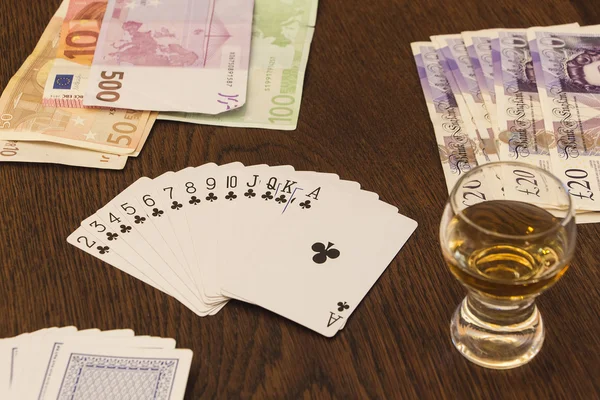 Vintage still life of playing cards, cash money and  shot of alc