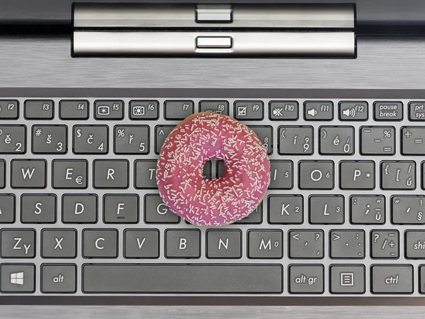 Клавиатура компьютера с розовым и сладким пончиком — стоковое фото