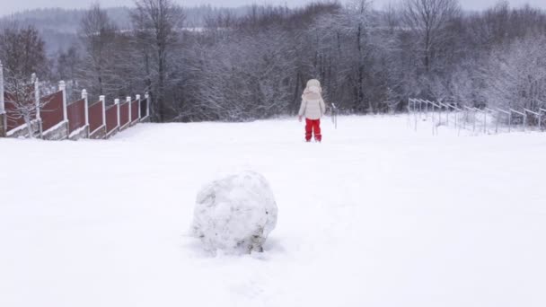 Mała dziewczynka biegająca na śnieżnym wzgórzu. Zabawa w zimową pogodę. — Wideo stockowe