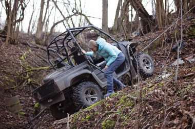 Bir kız, hendeğe doğru giden bir cipin yanında duruyor.