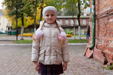 Okul üniformalı bir kız sokakta dikiliyor..