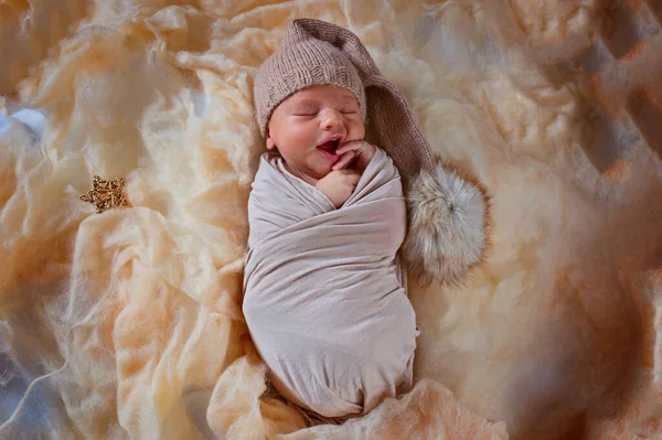 Recién nacido durmiendo bostezos bebé. Pequeño niño dormido en un traje con un pompón. —  Fotos de Stock