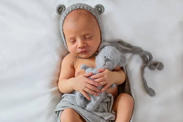 Retrato de un bebé recién nacido durmiendo con un juguete en un sombrero con orejas —  Fotos de Stock